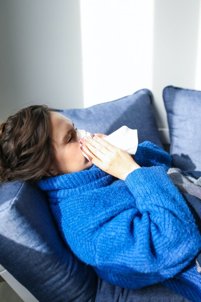 woman in blue sweater lying on bed taking sick leave